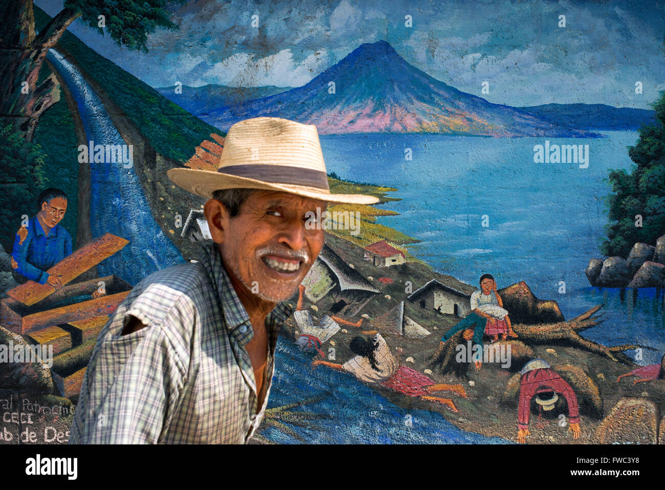 Homme marchant local devant un mur haletant dans San Juan La Laguna, Solola, Guatemala. Peinture art traditionnels mayas Santiago UN Banque D'Images
