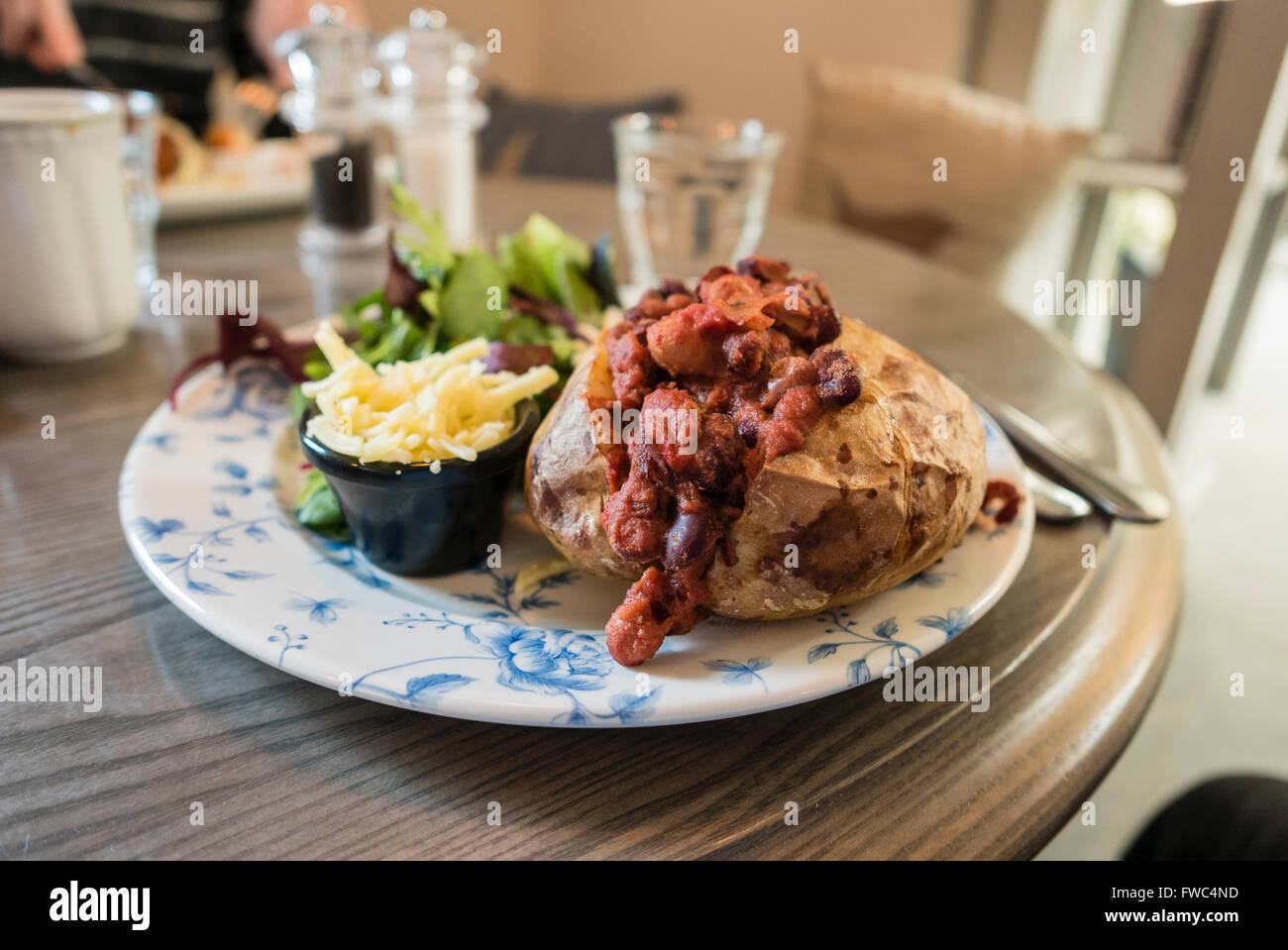 Chili végétarien-con-carne sur une pomme de terre au four avec du fromage vegan veste et salade dans un café. Banque D'Images