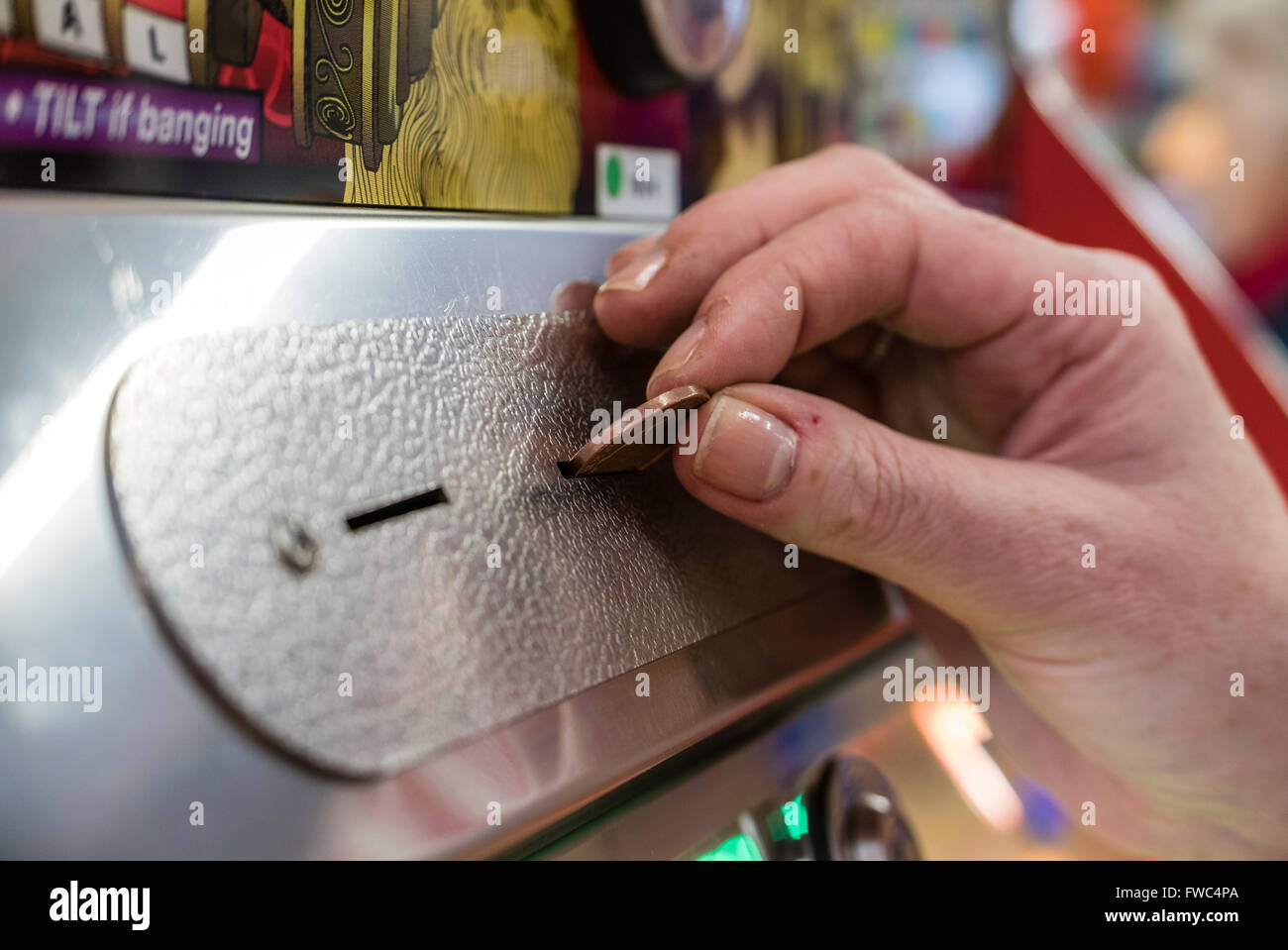 Une femme joue un 2p tuppeny nudger machine dans une fête foraine à une station balnéaire britannique. Banque D'Images
