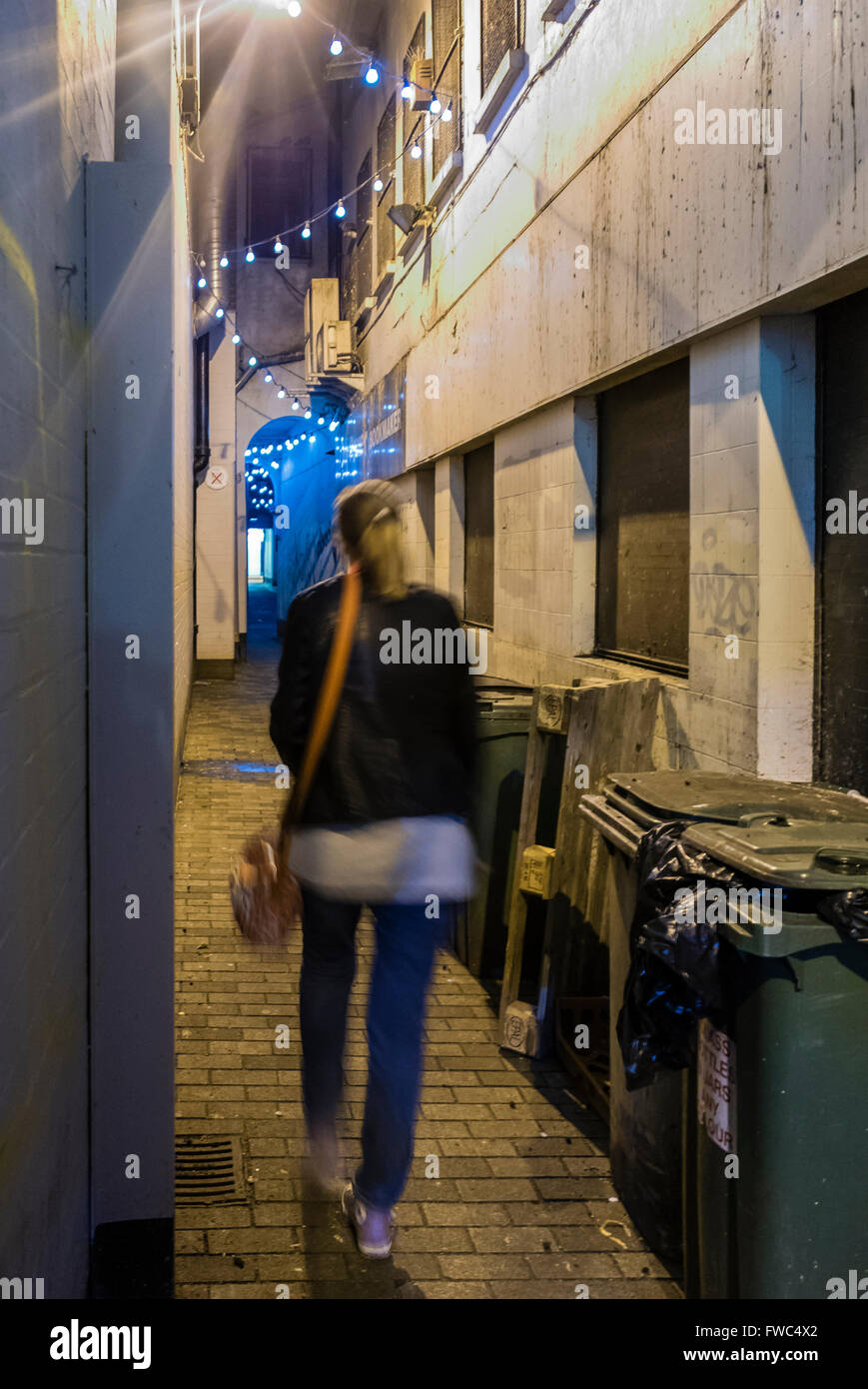 Une femme marche à travers l'entrée de la Couronne, l'un des 'Entrées' dans Belfast, composé de rues très étroites. Banque D'Images