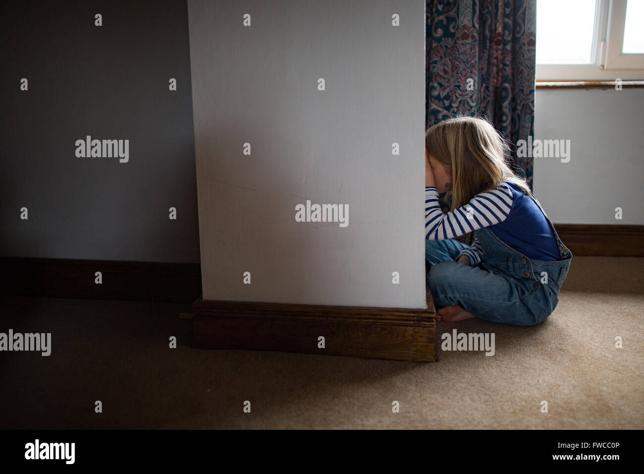 Un 7-year-old girl fait face au mur comme une punition pour être naughty Banque D'Images