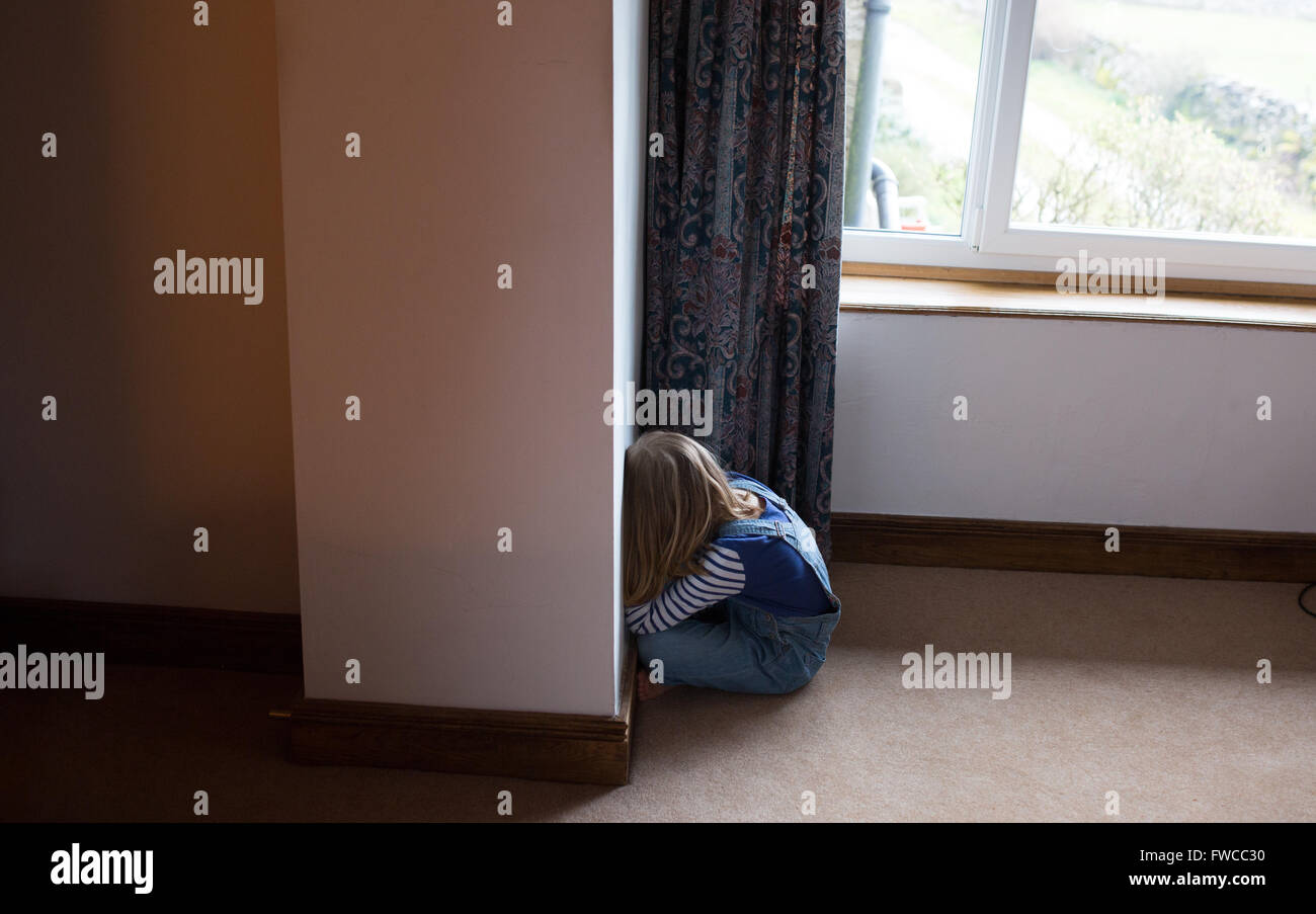 Un 7-year-old girl fait face au mur comme une punition pour être naughty Banque D'Images