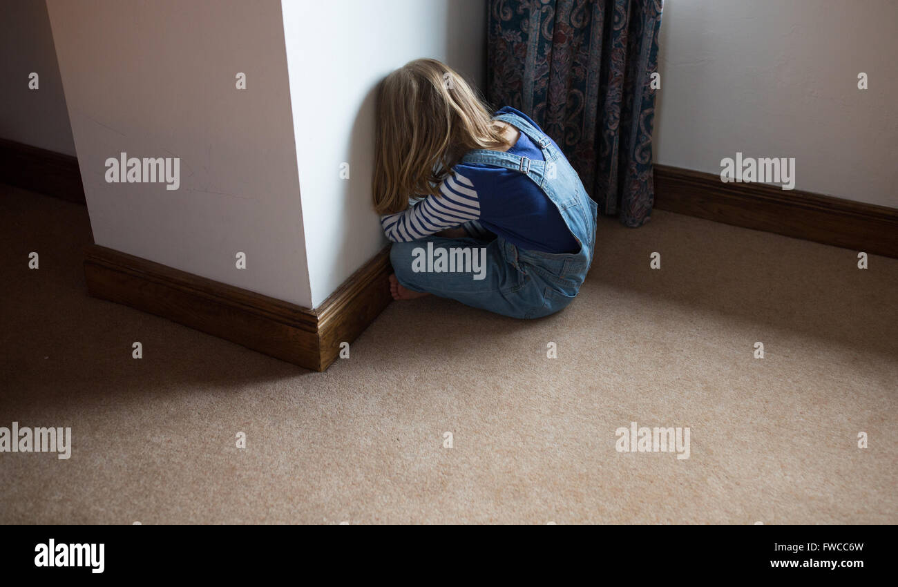 Un 7-year-old girl fait face au mur comme une punition pour être naughty Banque D'Images