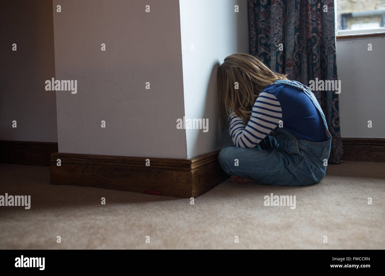 Un 7-year-old girl fait face au mur comme une punition pour être naughty Banque D'Images