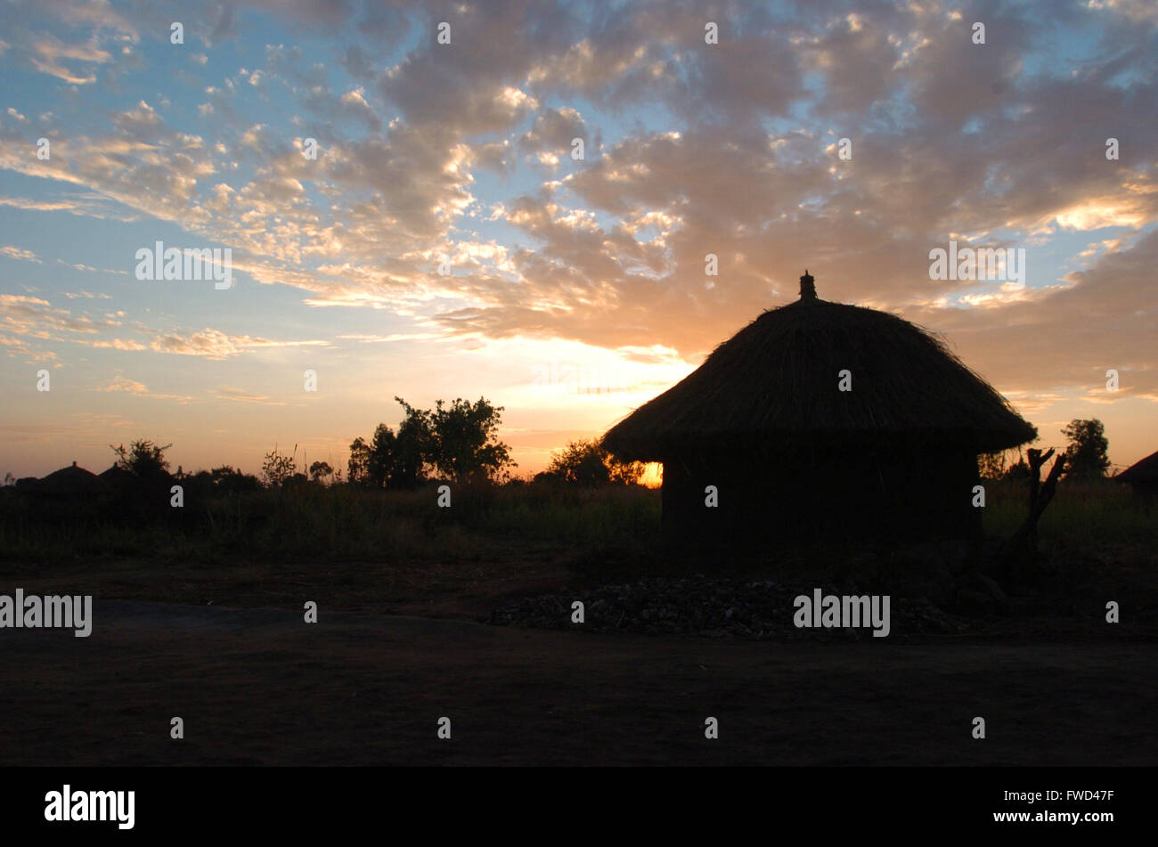 Lacekocot, district de Pader, en Ouganda. L'année 2009. Le soleil rouge se couche sur le paysage des huttes de boue et de palmiers à l'Lacekocot du Camp de personnes déplacées dans la région de Pader, au nord de l'Ouganda. Banque D'Images