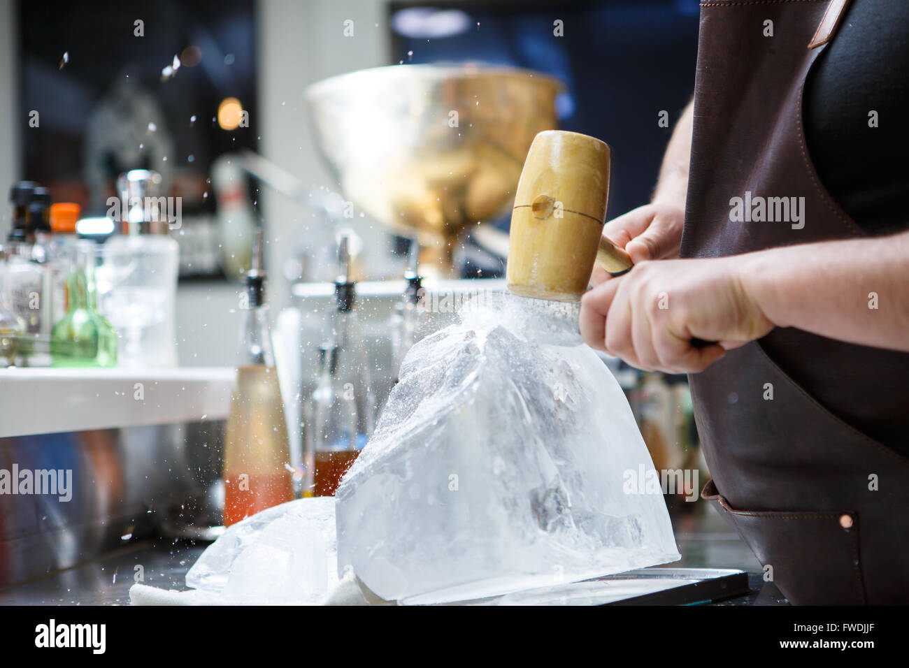 Barman mannually la glace concassée avec du marteau et couteau en métal. Banque D'Images