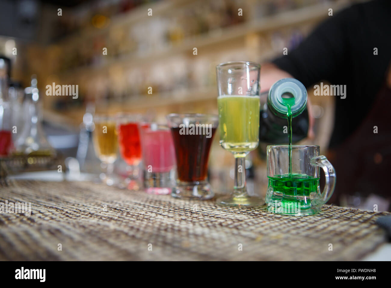 Barman verse divers d'alcool boire dans de petits verres sur bar Banque D'Images