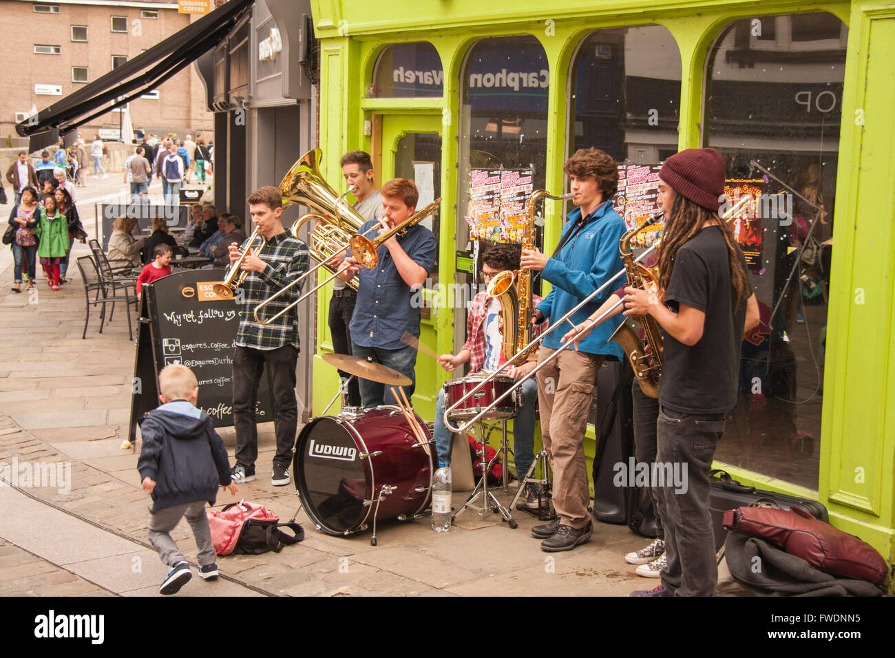 Jeune garçon faisant un don à une bande de rue de la rue dans le centre-ville de Durham en Angleterre, Royaume-Uni, Europe Banque D'Images