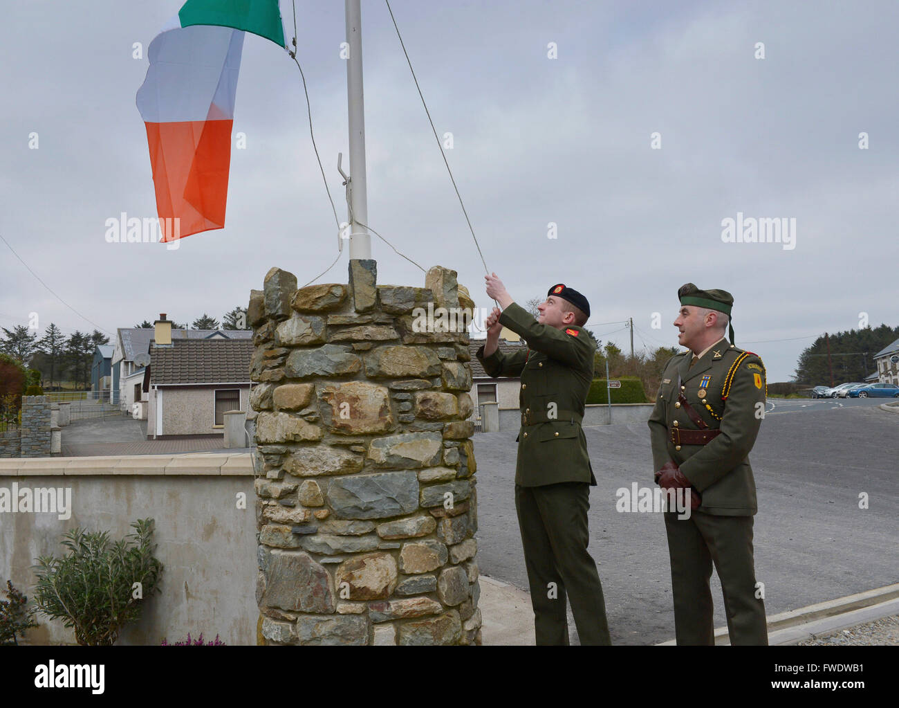 Les membres des Forces de défense irlandaises lever le drapeau tricolore, le drapeau de l'Irlande. Banque D'Images