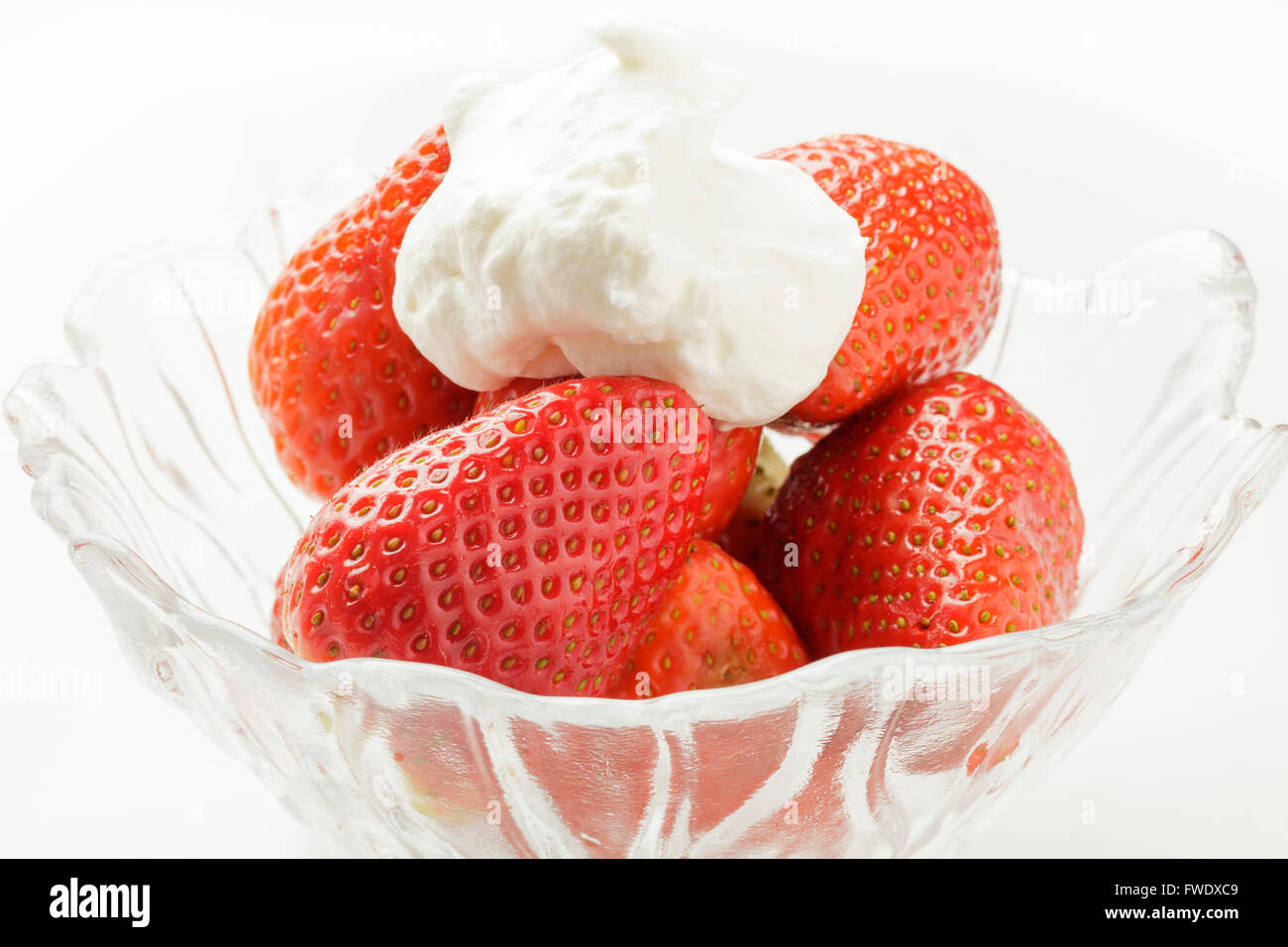 Les fraises fraîches et la crème dans un bol en verre Banque D'Images