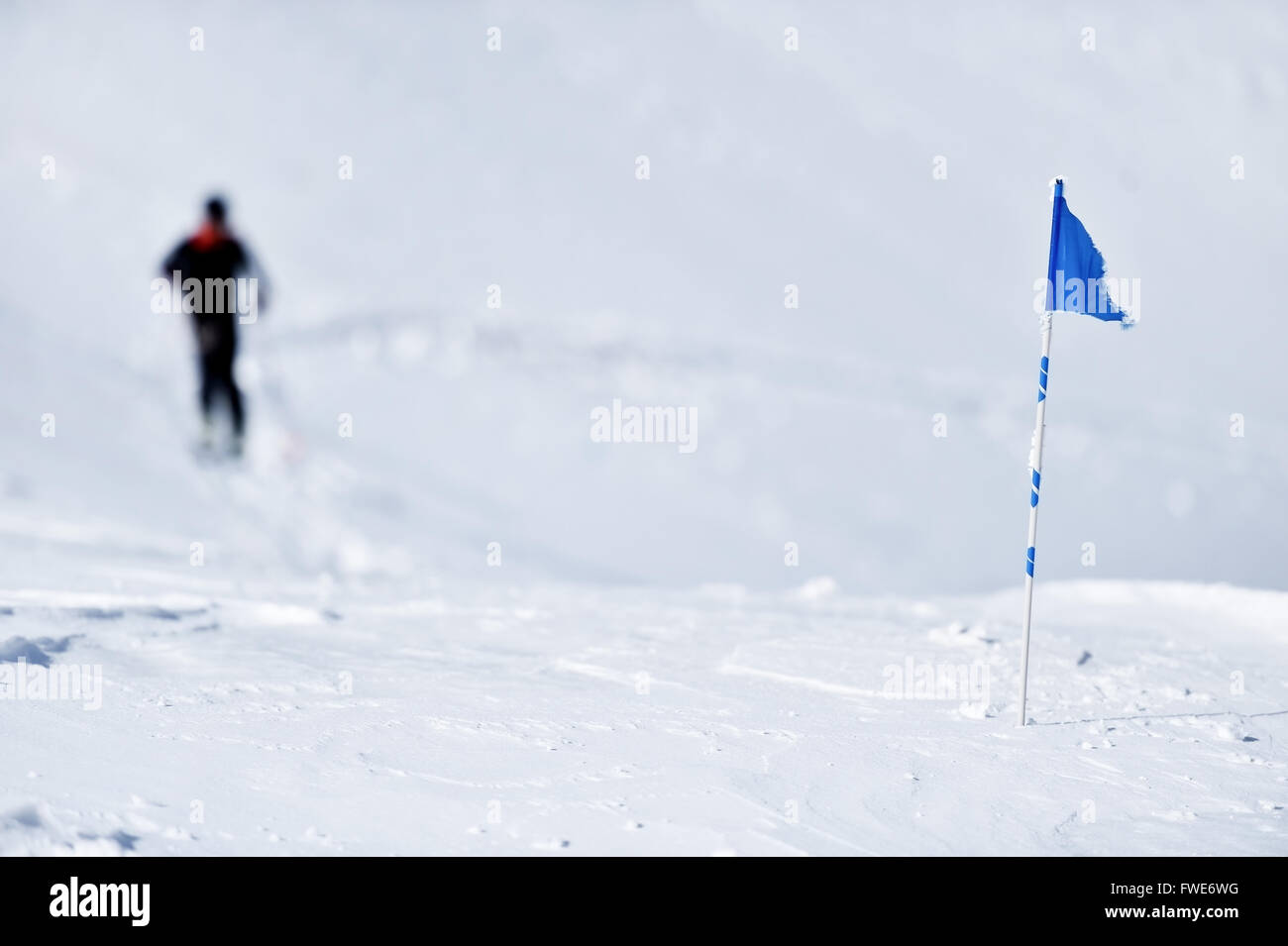 Drapeau bleu soufflé par le vent sur une montagne en hiver et skieur en arrière-plan Banque D'Images