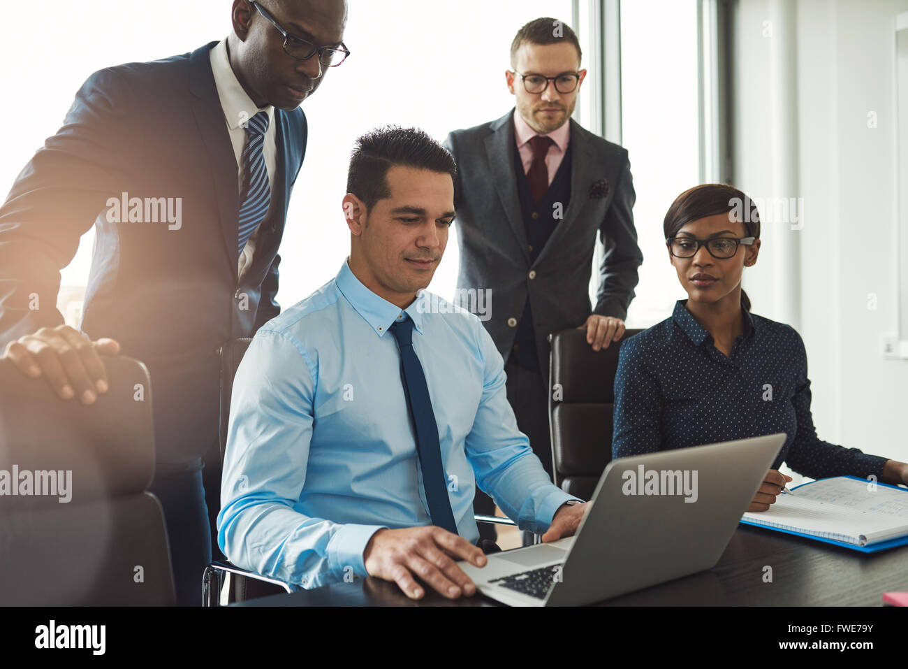 Groupe de gens d'affaires de divers vêtements à l'intérieur de leur bureau officiel de négocier ou de regarder l'information sur un ordinateur portable calculer Banque D'Images