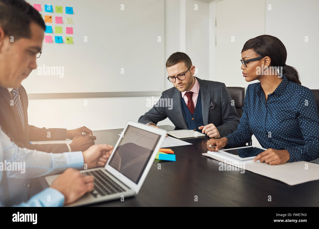 Groupe de collègues d'affaires multiracial dans une réunion autour d'une table dans le bureau de travailler sur des ordinateurs portables et de la paperasserie Banque D'Images