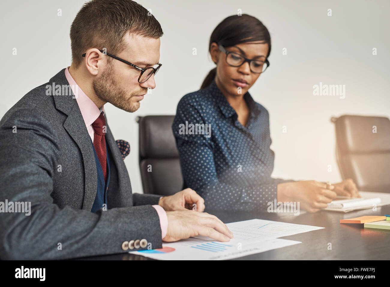 Les femmes d'affaires et avoir une réunion sérieuse siégeant ensemble la lecture d'un document ou un rapport avec l'accent d'un jeune homme en glasse Banque D'Images