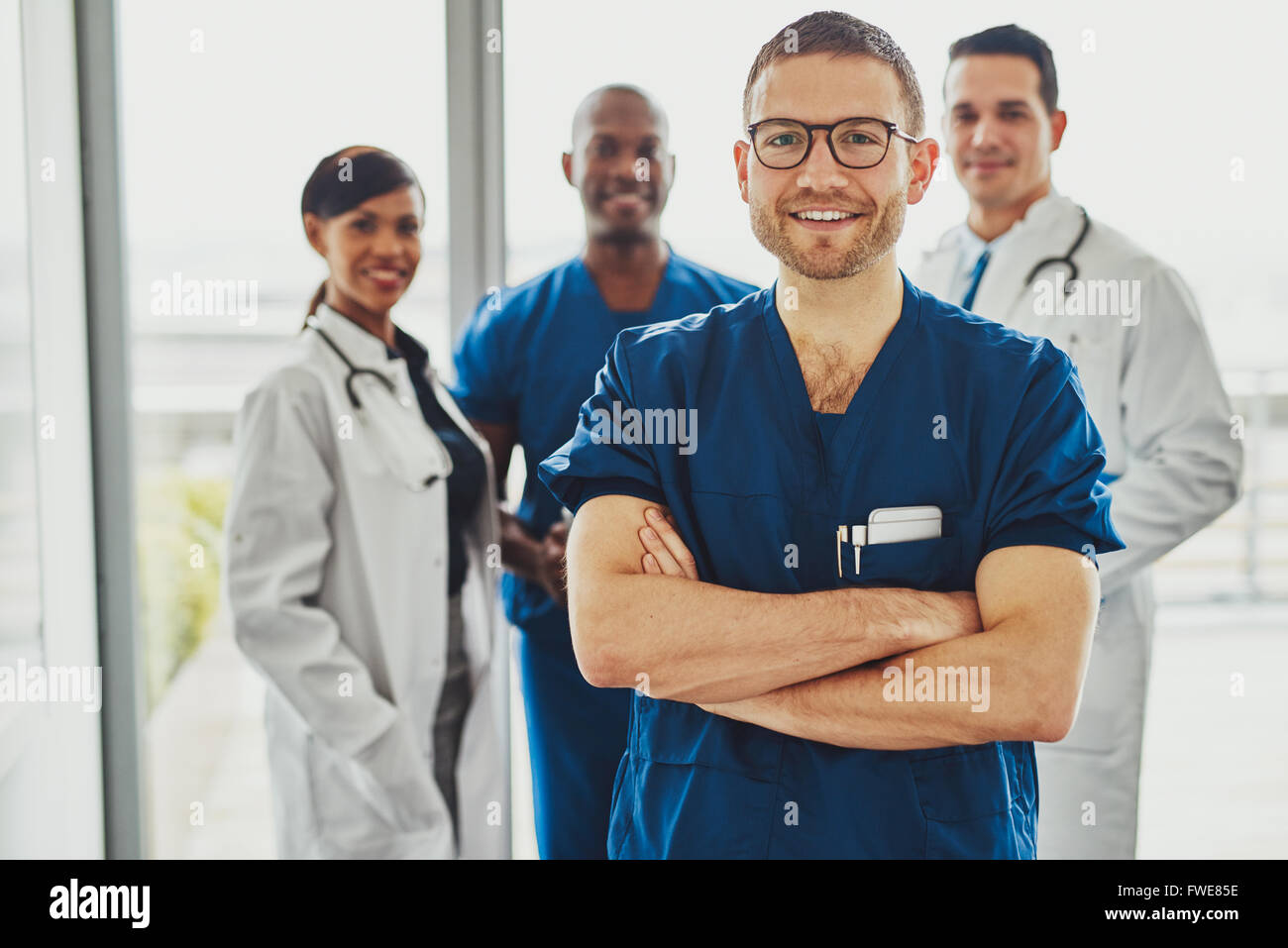 Certain médecin en face de group smiling at the camera, portant des vêtements chirurgien Banque D'Images