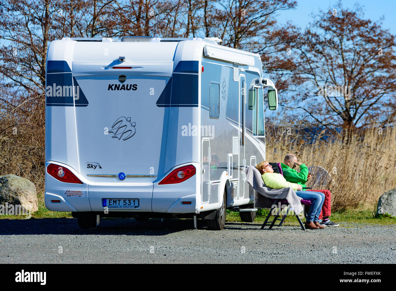 Kivik, Suède - 1 Avril 2016 : Deux personnes s'asseoir au soleil au soleil à l'extérieur d'un Fiat 2014 Knaus K250. L'homme est looking at mobile Banque D'Images Kivik, Suède - 1 Avril 2016 : Deux personnes s'asseoir au soleil au soleil à l'extérieur d'un Fiat 2014 Knaus K250. L'homme est looking at mobile Banque D'Images