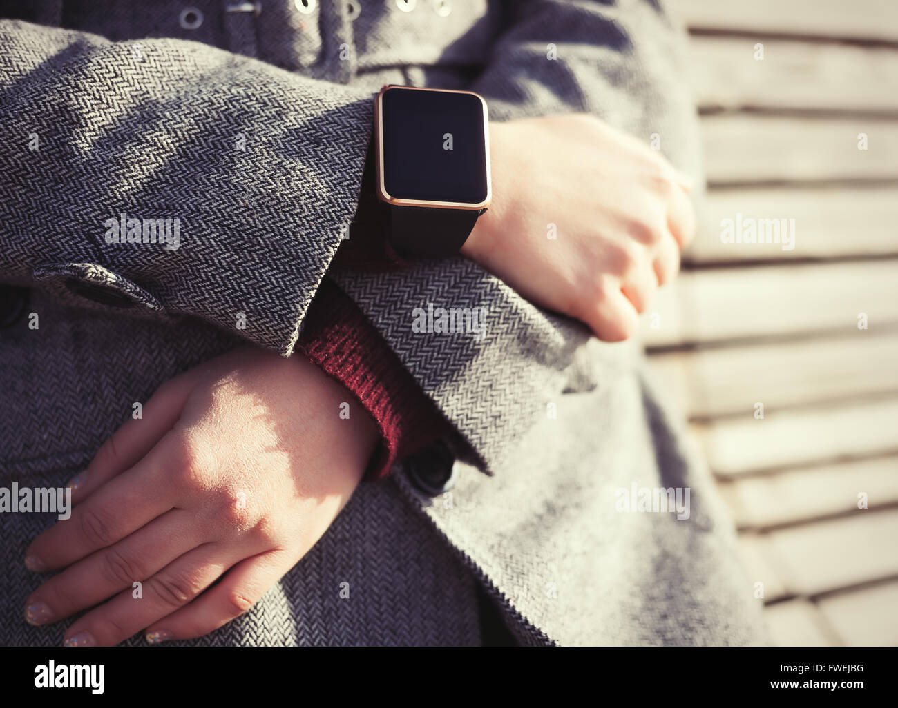 Femme en manteau gris portant des smart noir élégant montre-bracelet. Cette personne est toujours connecté à internet et médias sociaux. La technologie moderne et vintage faing tonifiant film Banque D'Images