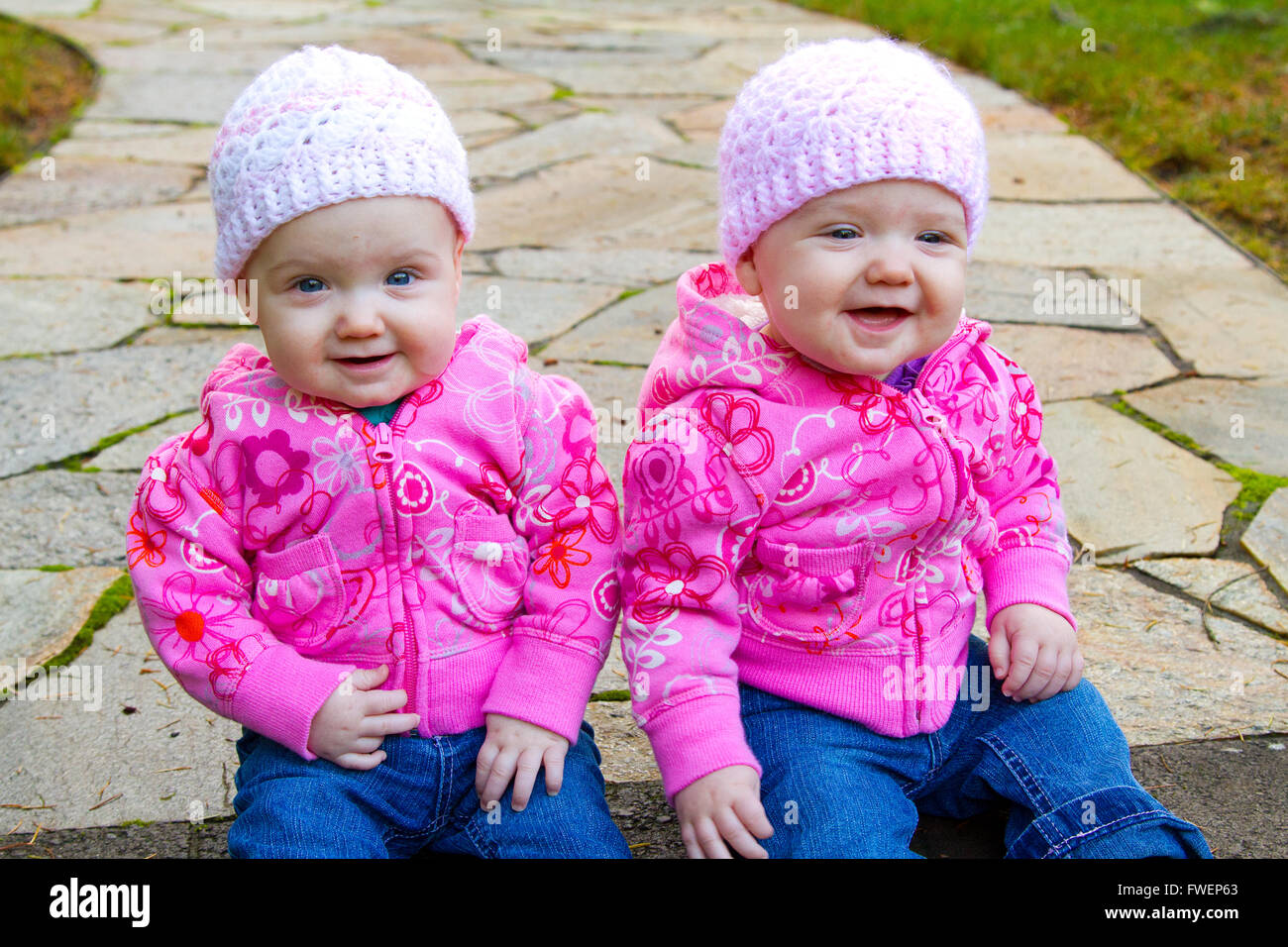 Lits bébé filles s'asseoir sur une pierre ronde portant des sweat-shirts et shorts rose. Banque D'Images