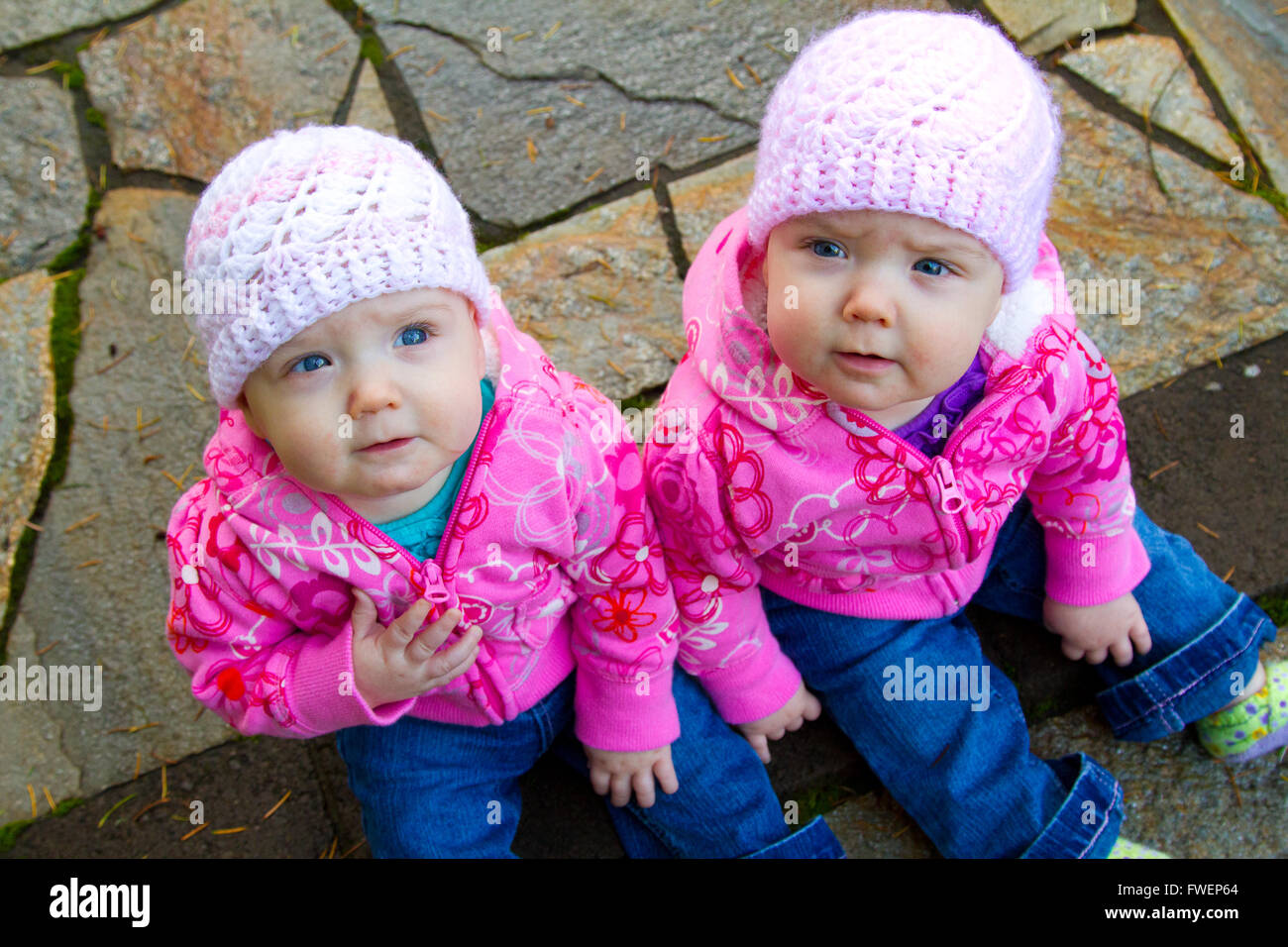 Lits bébé filles s'asseoir sur une pierre ronde portant des sweat-shirts et shorts rose. Banque D'Images