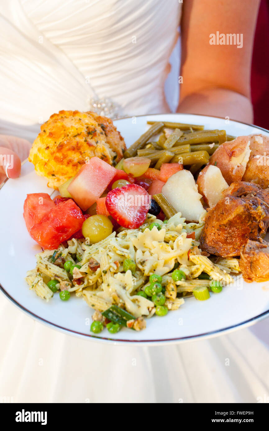 Le repas d'une épouse le jour de son mariage a l'air en bonne santé et bien cuisinés avec des pommes de terre, des fruits, de la salade de pâtes, haricots verts, poulet et Banque D'Images