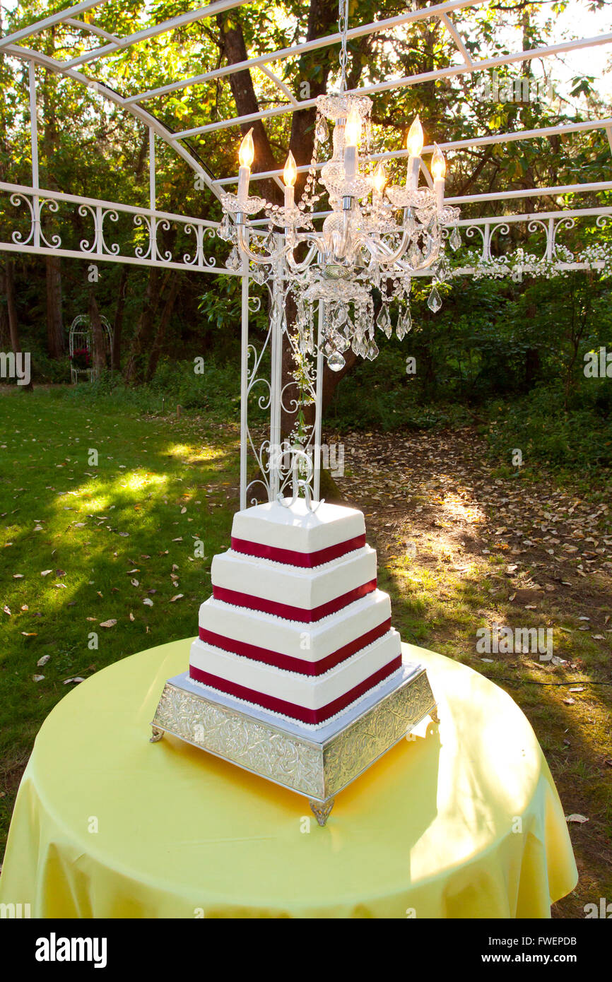 Un Carre Rouge Et Blanc Gateau De Mariage Avec Plusieurs Niveaux Et La Lettre R Sur Le Haut Se Trouve A L Exterieur Sur Une Table Jaune Pour Un Mariage Loisir Photo Stock