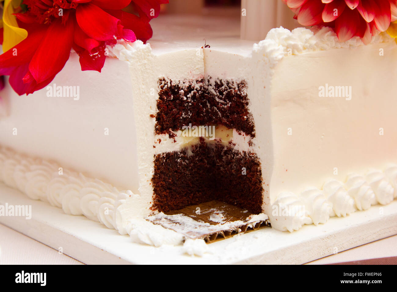 Un gâteau avec une part importante prise par les mariés après ils ont coupé le gâteau. Banque D'Images