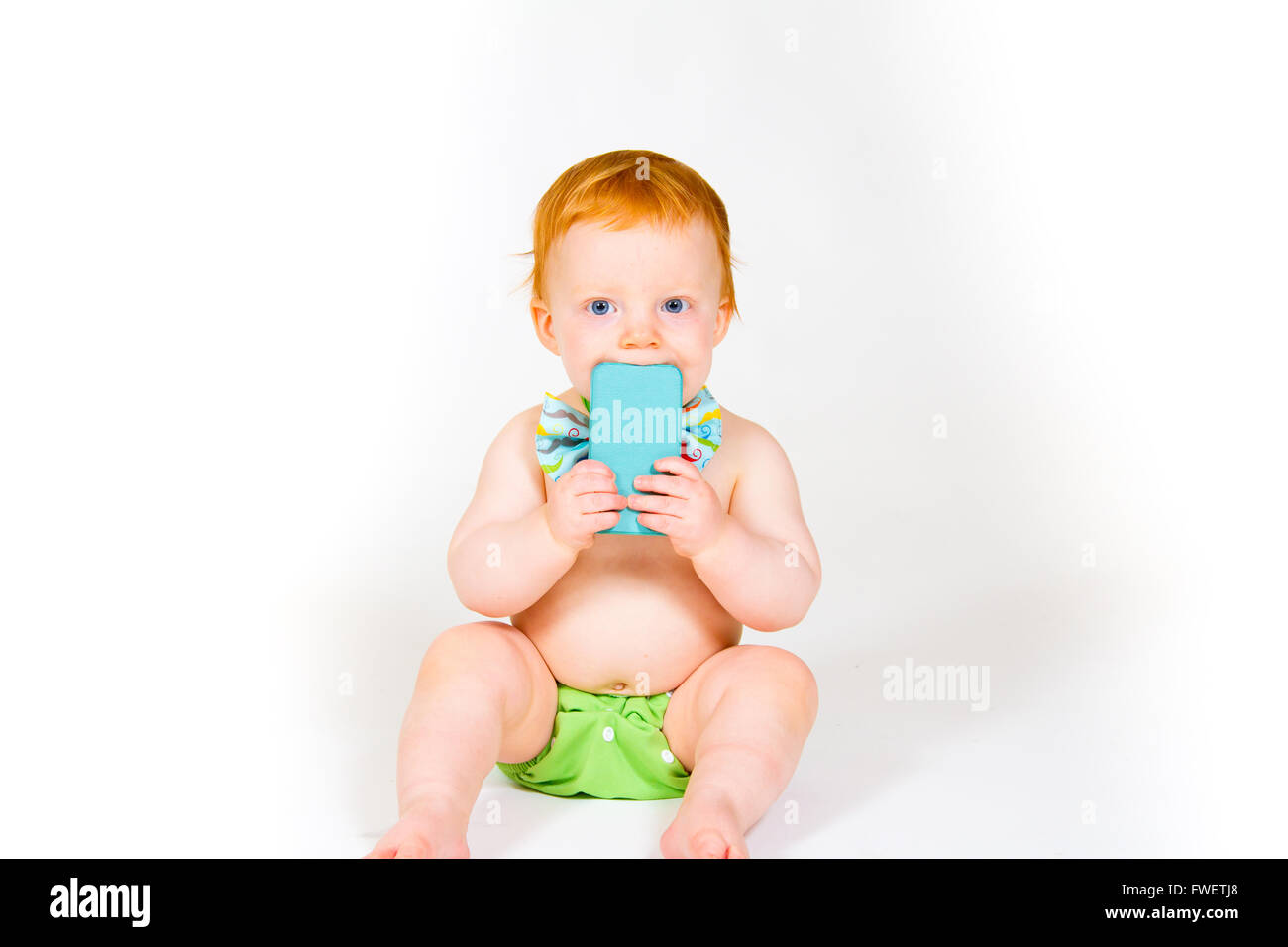 Un garçon âgé d'un an joue avec un téléphone cellulaire dans le studio avec un fond blanc. Banque D'Images