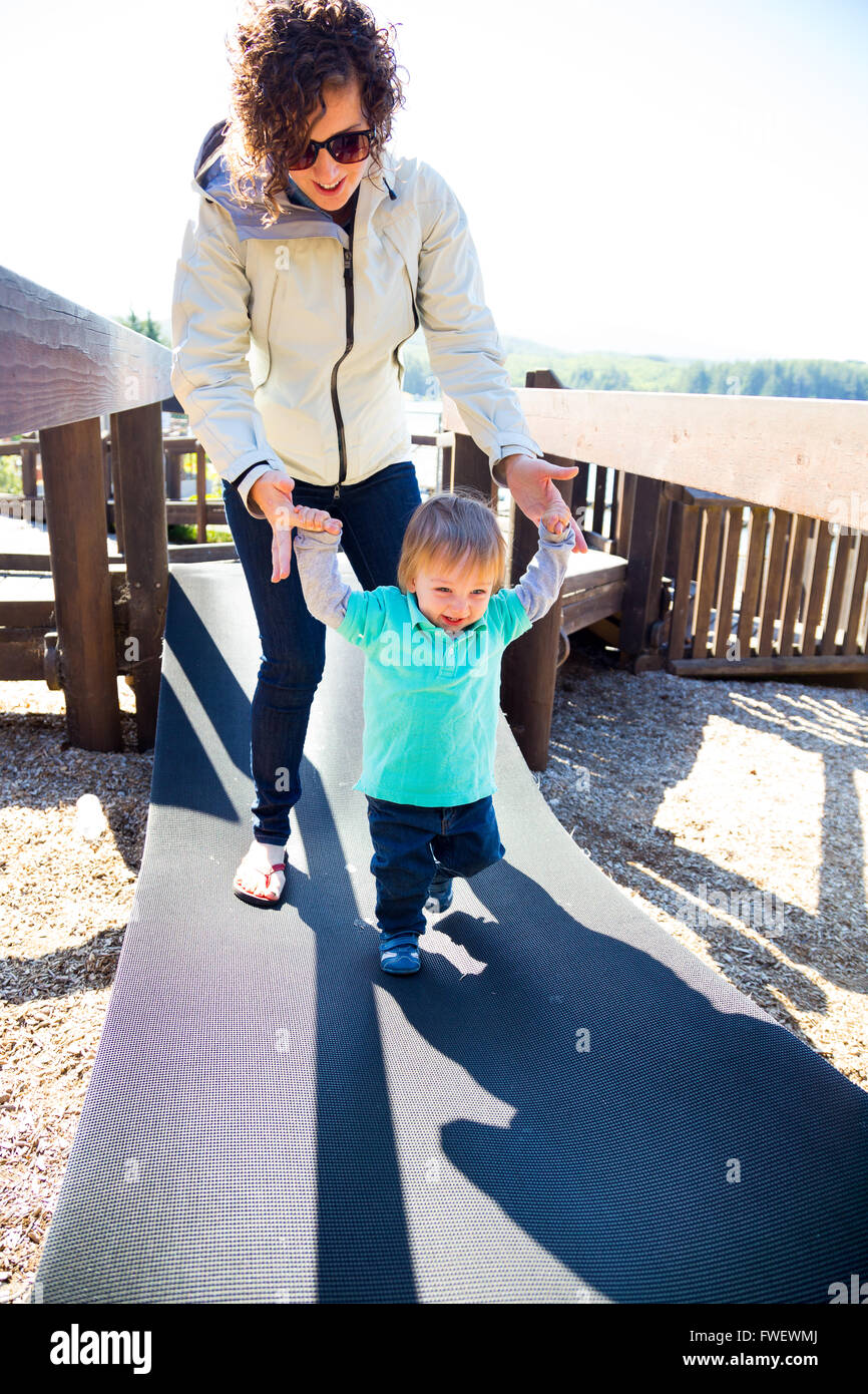 Une maman et son fils traverser un pont instable dans un terrain ensemble. Banque D'Images