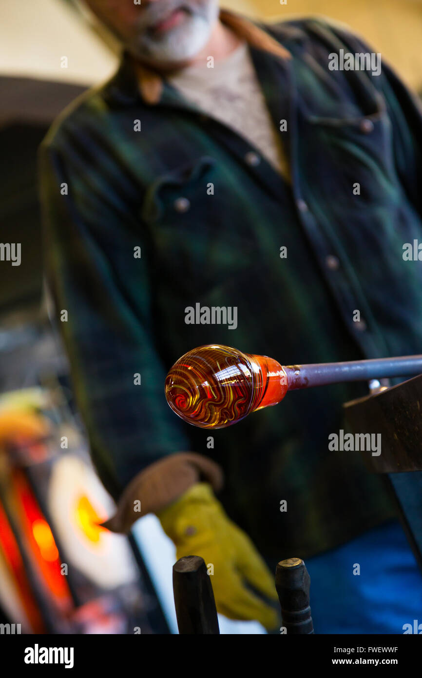 Quelqu'un de très talentueux verrier se forme et façonner le verre dans un atelier de fabrication du verre. Il est en train de créer un bol cannelé à partir de l'ip Banque D'Images