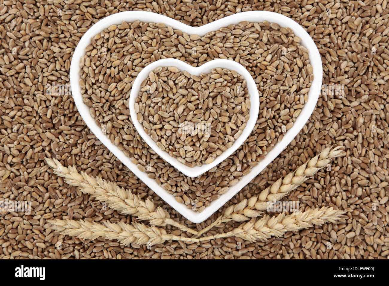 Le grain de blé dans l'alimentation des bols en forme de coeur avec les gaines formant un motif de fond. Banque D'Images