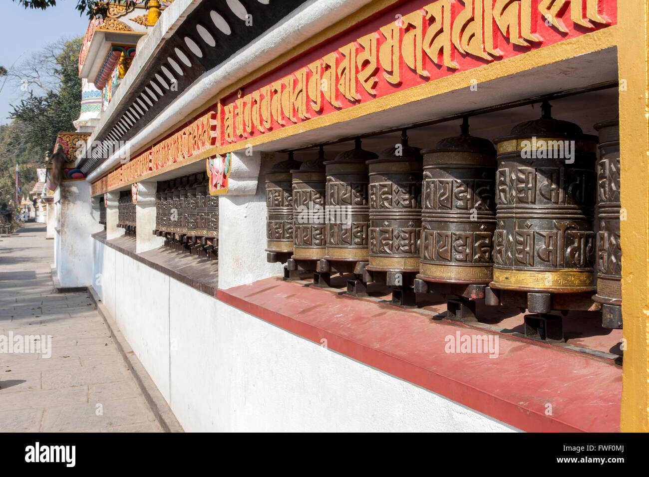 Le Népal, Katmandou, Swayambhunath. Roues de prière bouddhiste Line le mur autour du stupa à la base de la colline. Banque D'Images