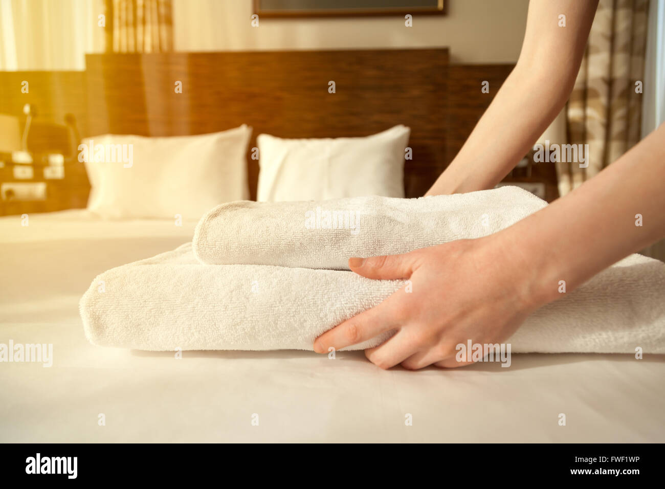 Close-up des mains mettre pile de serviettes de bain blanc frais sur le drap. Prix Femme de chambre de service. Flair de l'objectif Banque D'Images