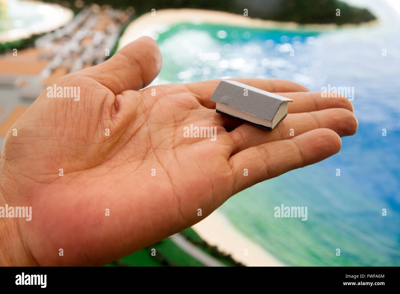Petite maison dans la main. Main tenant une maison. Big replica en arrière-plan Banque D'Images