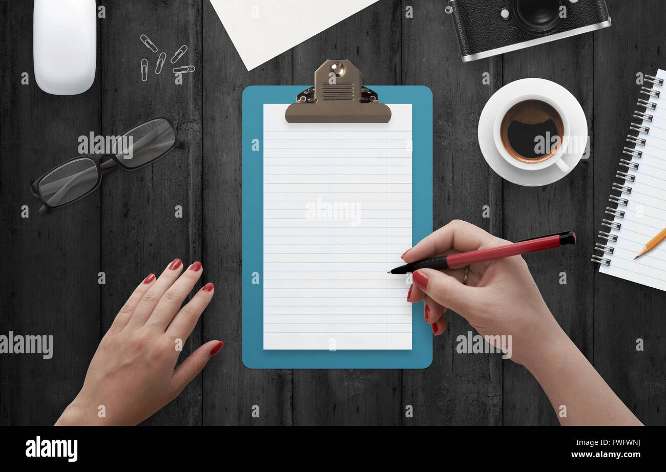 L'écriture sur main de femme entouré d'ordinateurs portables avec accessoires de bureau. Vue de dessus de bureau. Le café, verres, crayon, papier, souris Banque D'Images