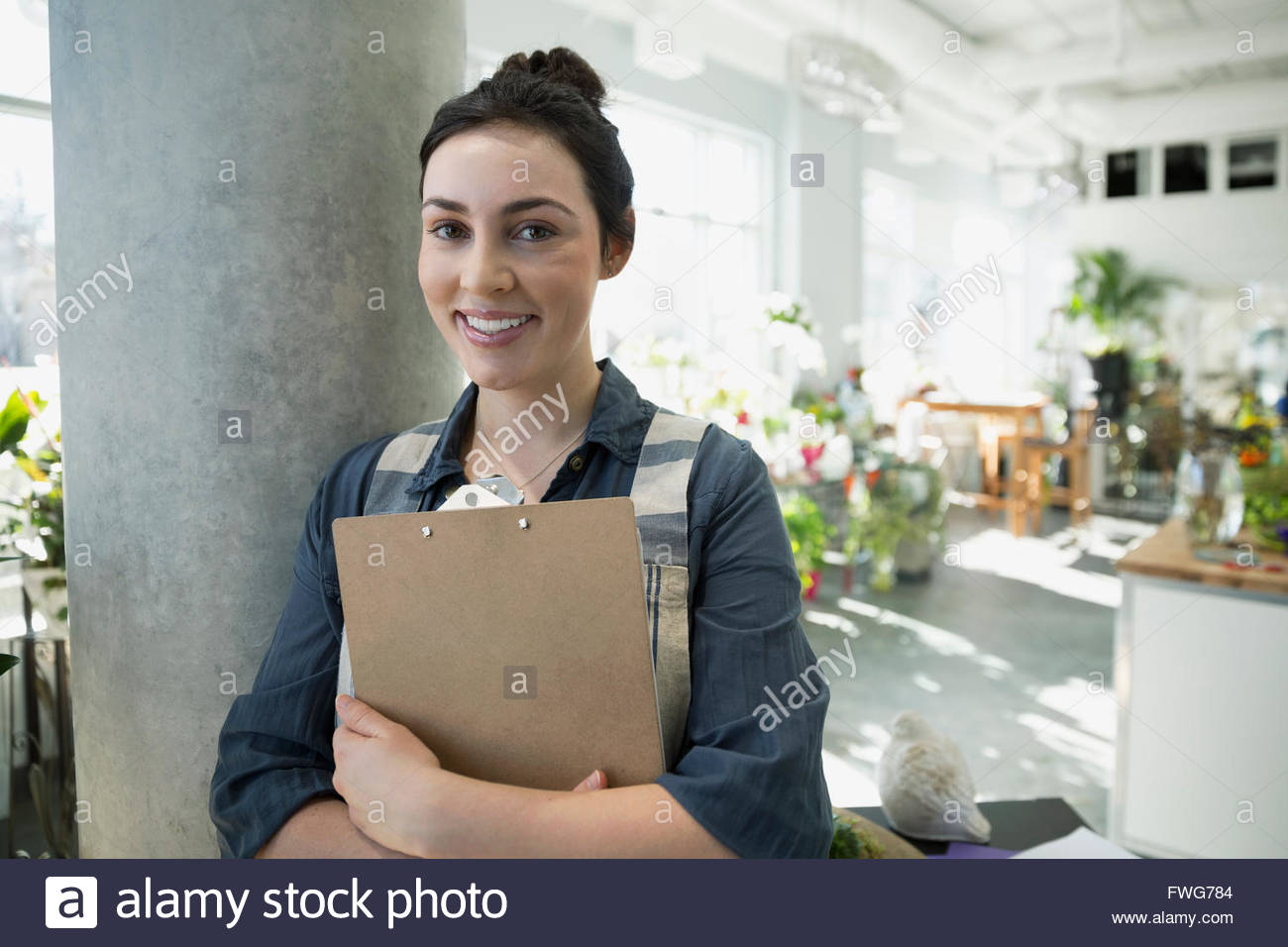Portrait smiling florist avec presse-papiers dans le magasin de fleurs Banque D'Images