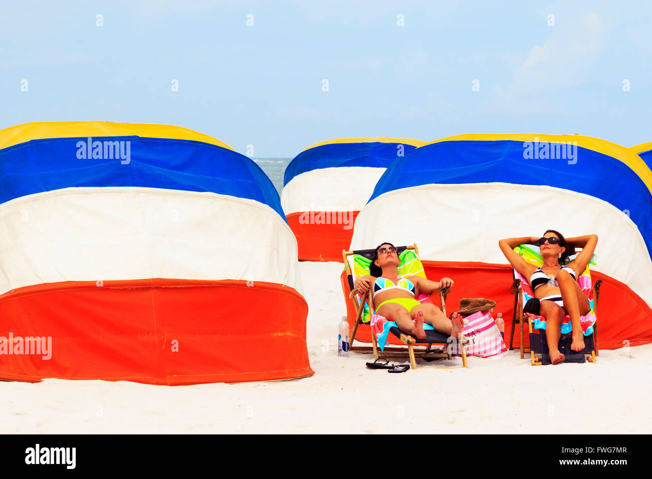 Deux femmes de soleil à côté du brise-vent multicolores sur la plage de Clearwater, Floride, USA Banque D'Images