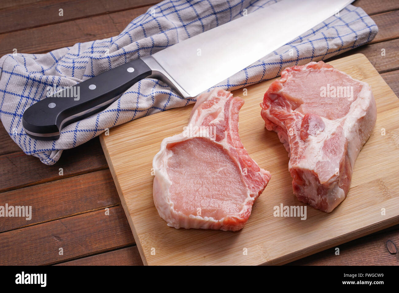 Côtelettes de porc cru, allongé sur une planche de bois pour la cuisson Banque D'Images