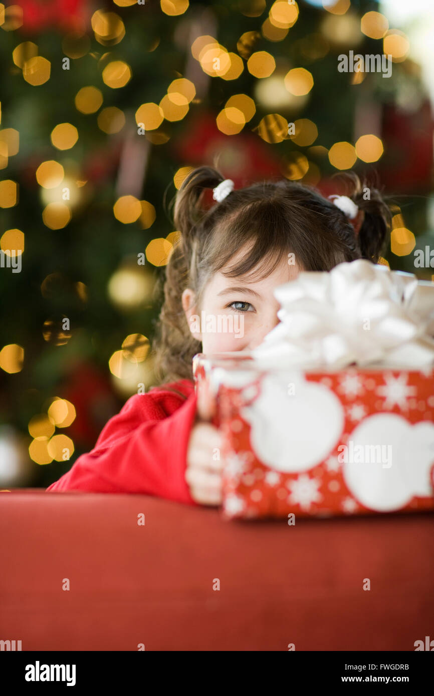Une fille par une presse Noël cachant son visage derrière une grande parcelle. Banque D'Images