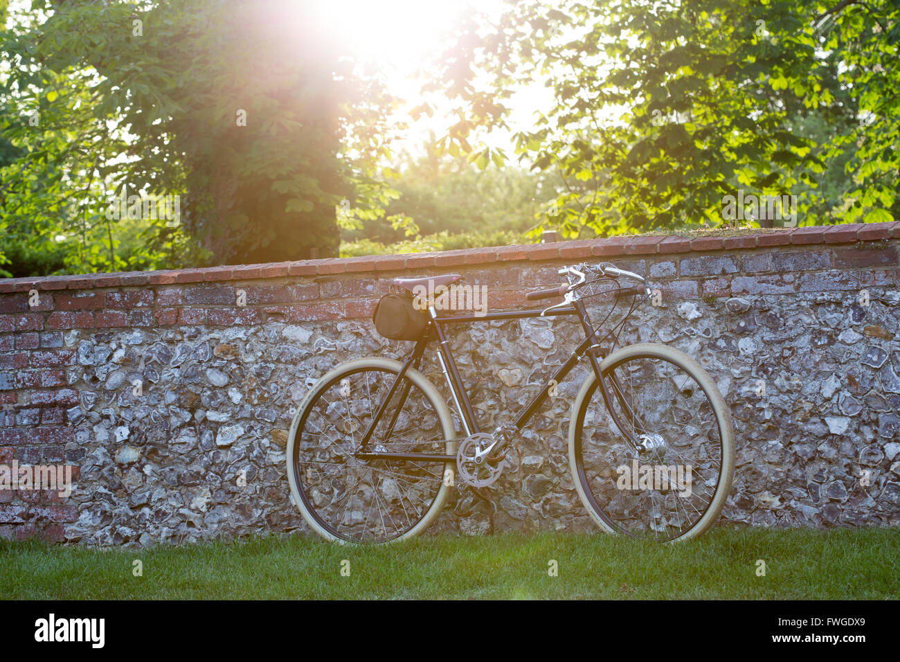 Un style vintage racer bike s'appuya contre un mur de briques et silex Banque D'Images