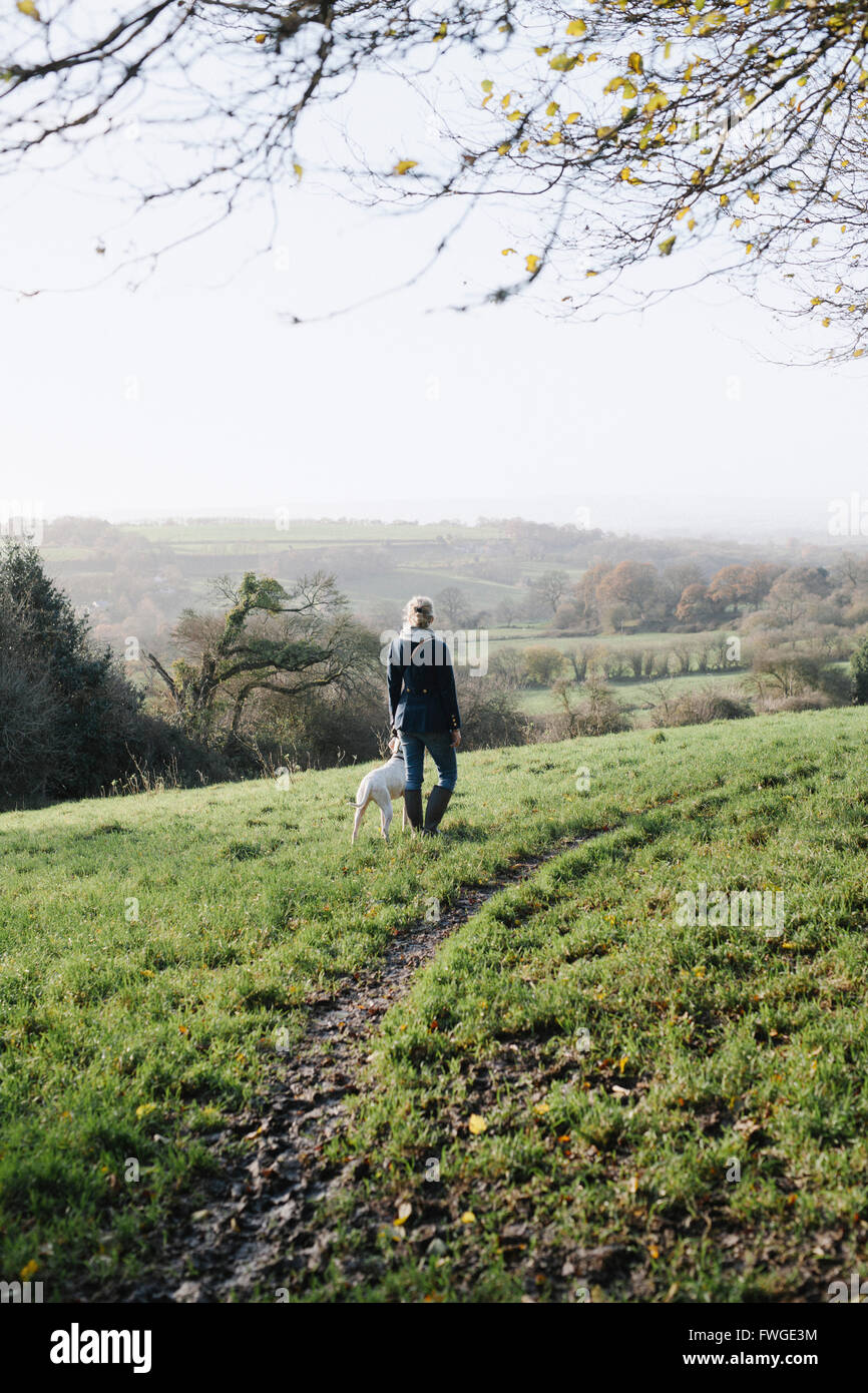 Une femme marche avec un chien sur un promontoire donnant sur la campagne. Banque D'Images