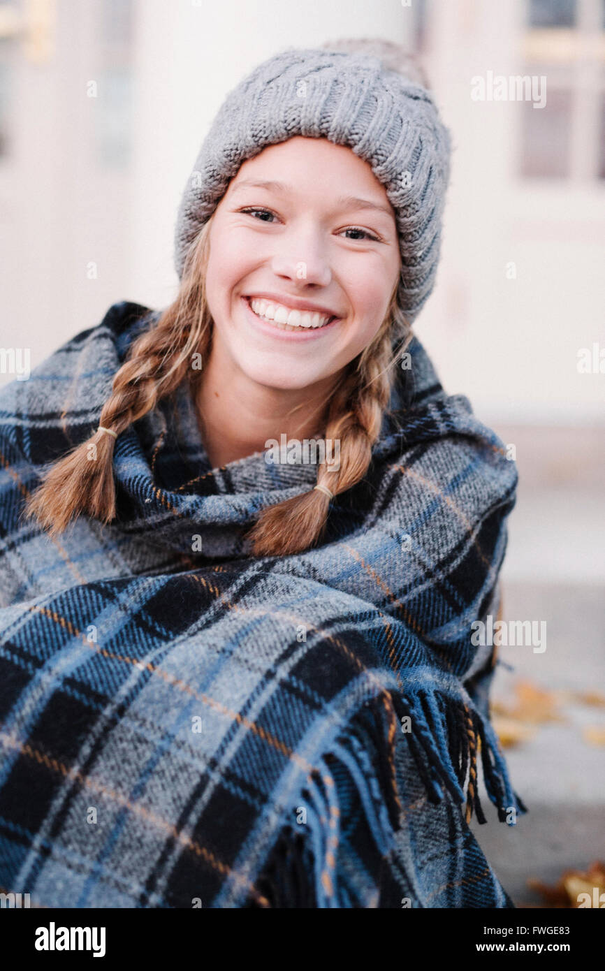 Une adolescente dans un châle plaid tartan et woolly hat à l'extérieur l'hiver. Banque D'Images