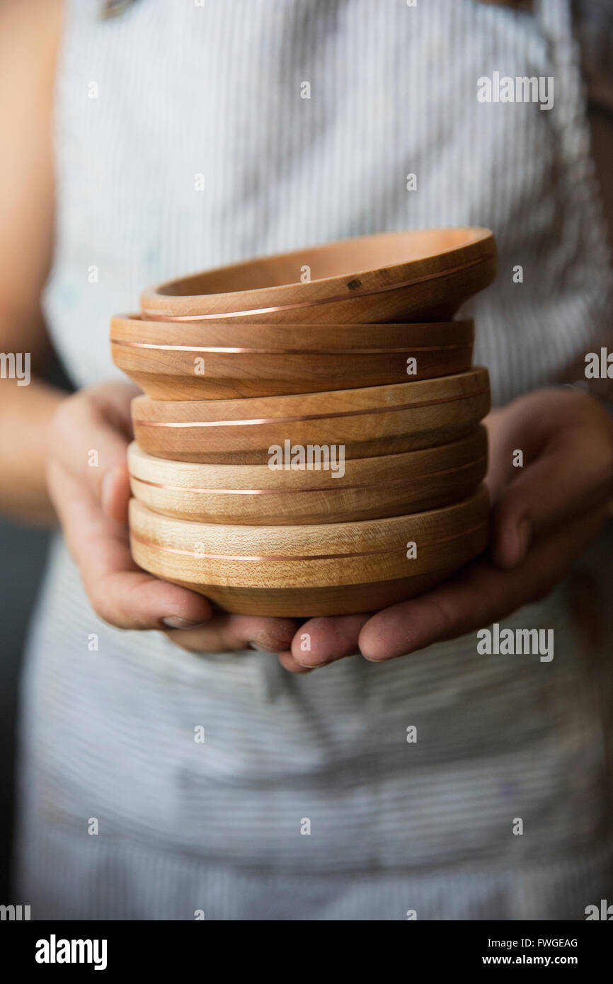 Un tanneur tenant une pile de bois tourné bols ou plats. Banque D'Images