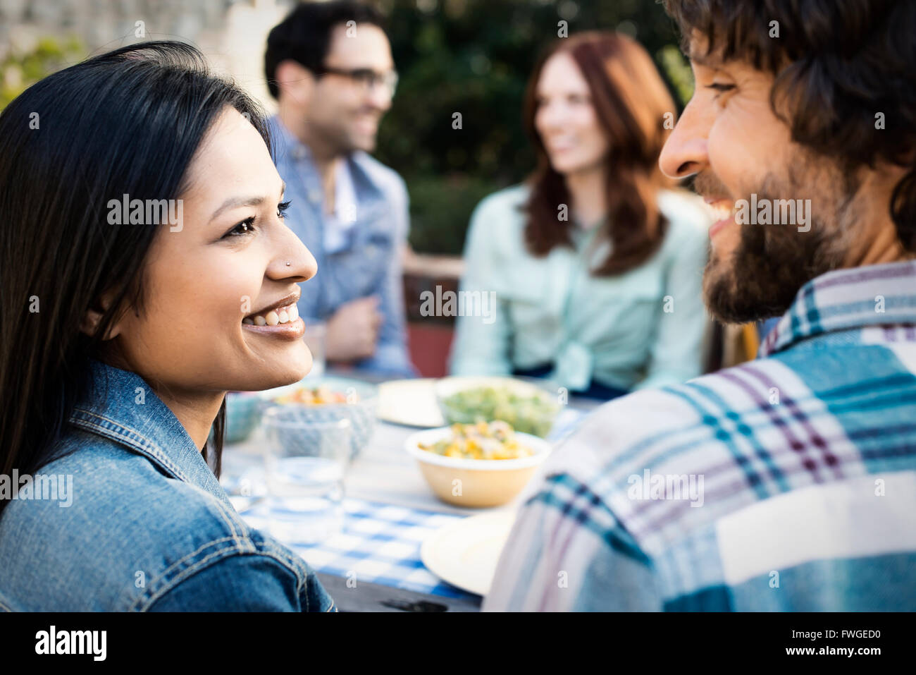 Autour d'une table d'amis, hommes et femmes de rire et de parler. Banque D'Images