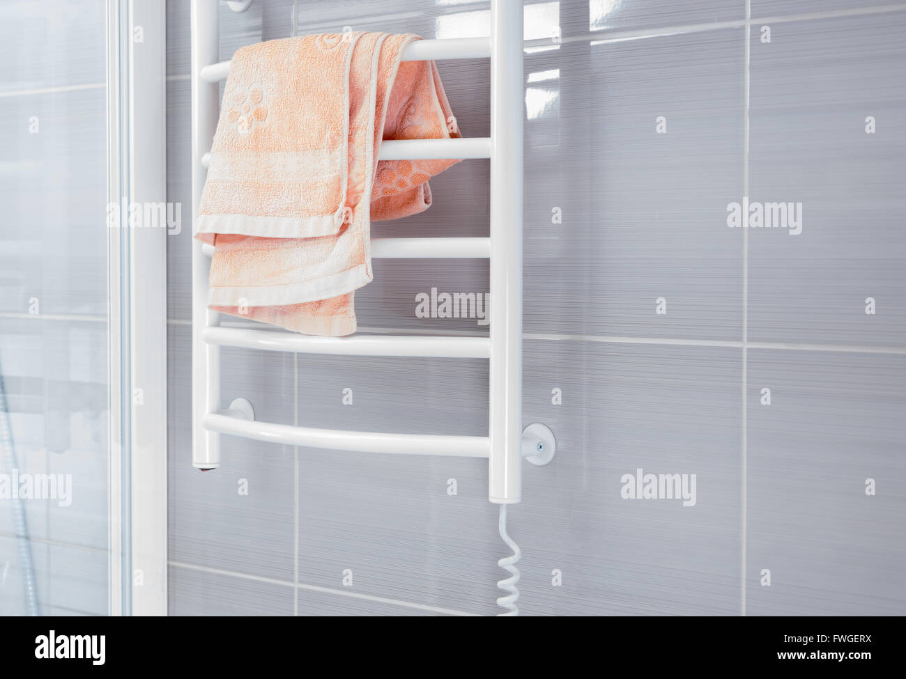 Vide salle de bains avec douche de couleur gris métal blanc derrière mur grille de réchauffage avec serviette rose pliée à haut Banque D'Images