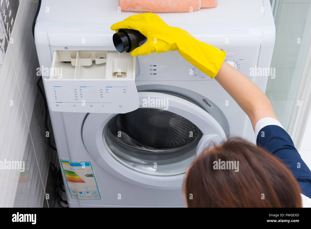 Woman pouring adoucissant dans un lave-linge avec des gants pendant qu'elle  fait le ménage, high angle vue rapprochée Photo Stock - Alamy