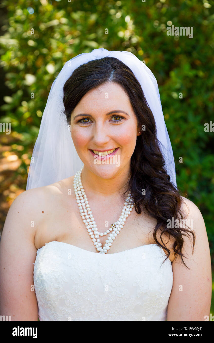 Une fiancée pose pour des portraits tout en portant sa robe de mariage dans un parc à l'extérieur juste avant la cérémonie de mariage ici. Banque D'Images