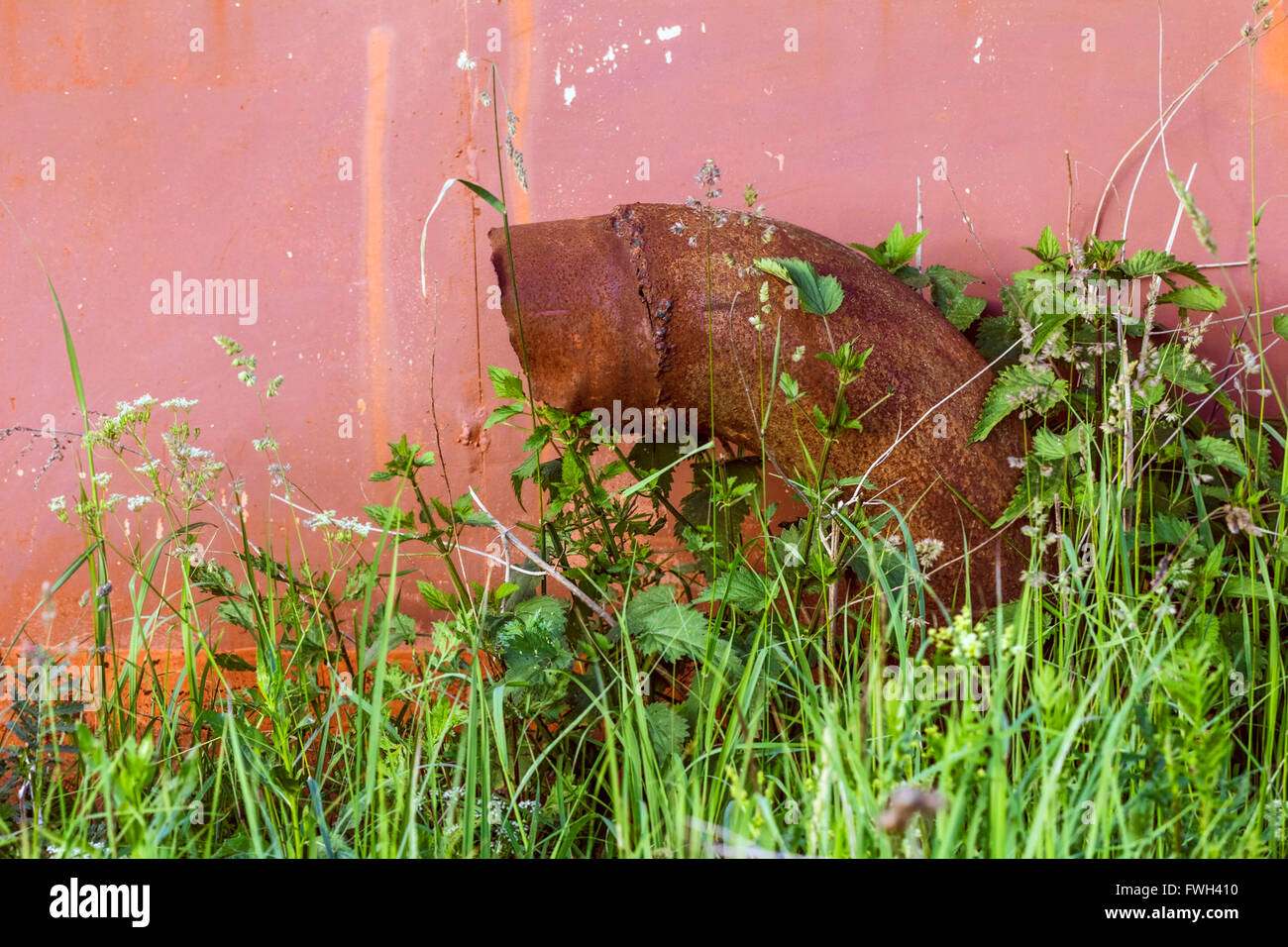 Tuyau rouillé sur fond de vieux garage rouge Banque D'Images