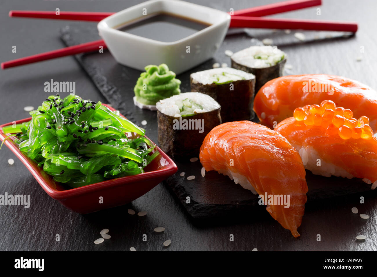 Des sushis et des rouleaux d'une seasalad vert sur une table d'ardoise. Banque D'Images