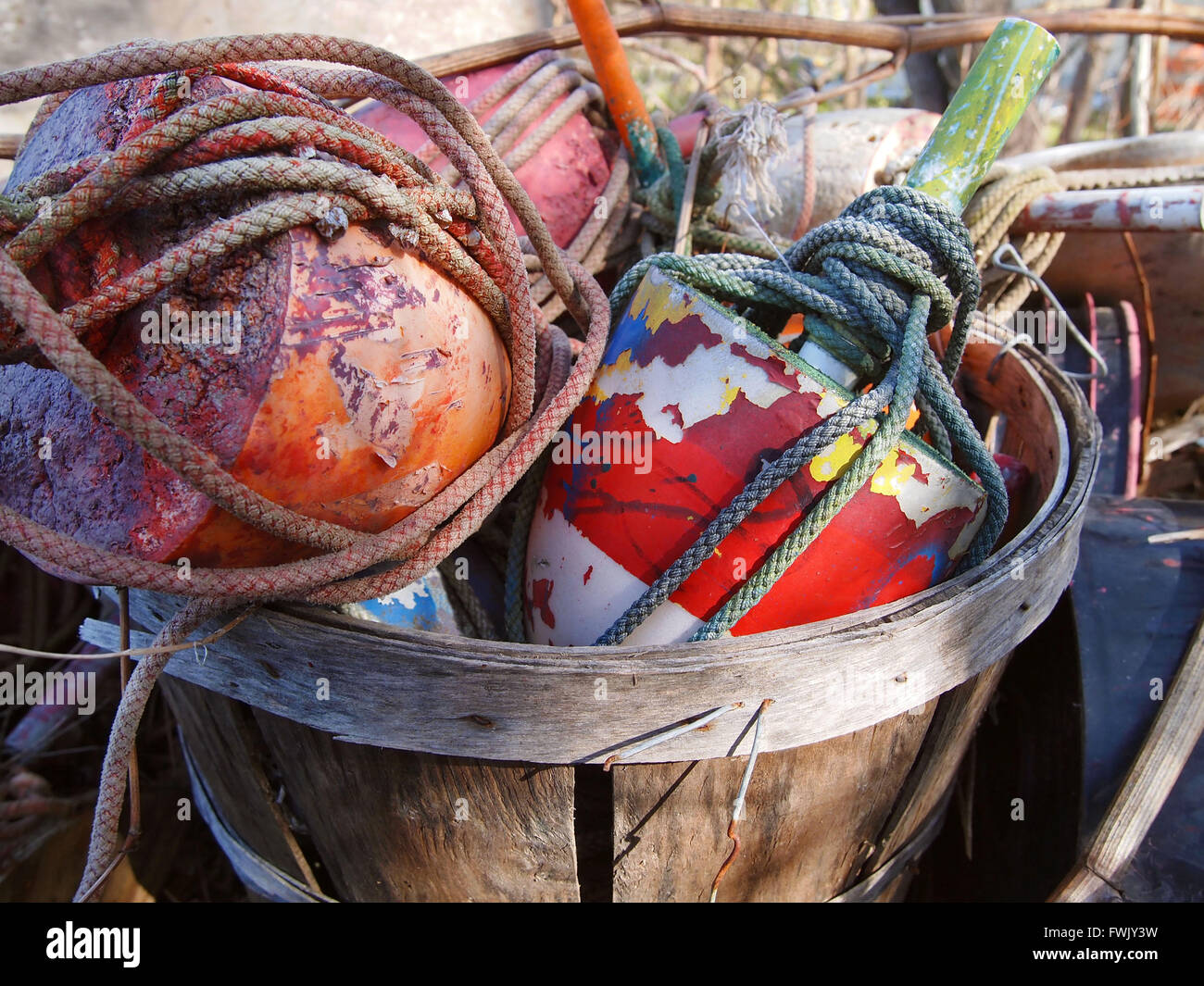 Un boisseau de crab pot ancien coloré des bouées et des cordes de bateau à l'extérieur dans la lumière du soleil. Banque D'Images