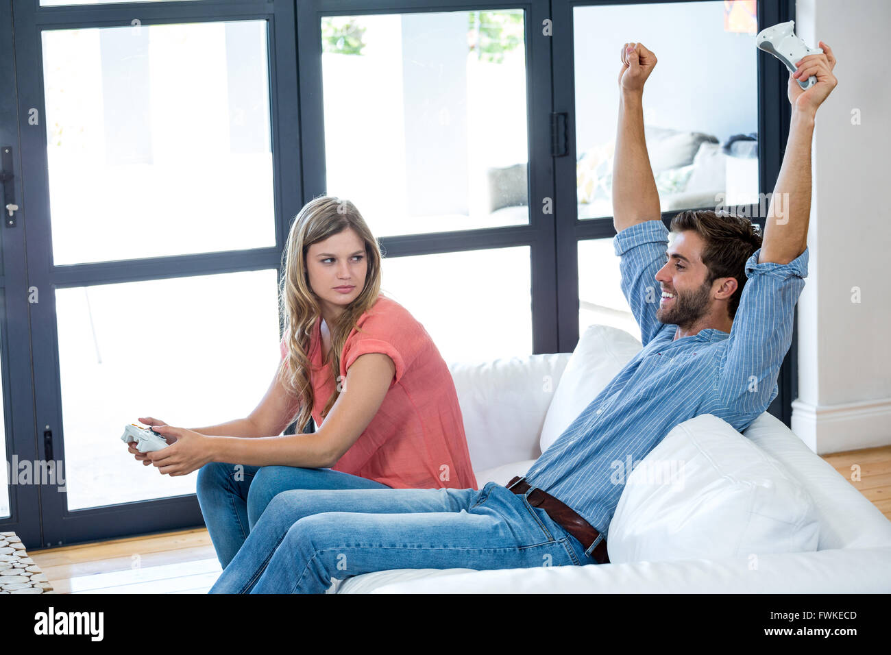Smiling man with arms raised après avoir remporté le jeu vidéo Banque D'Images
